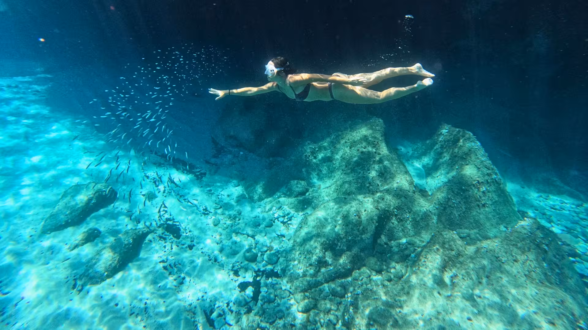 Woman snorkeling in crystal-clear waters of Cala Gonone, Orosei Gulf, surrounded by vibrant marine life.