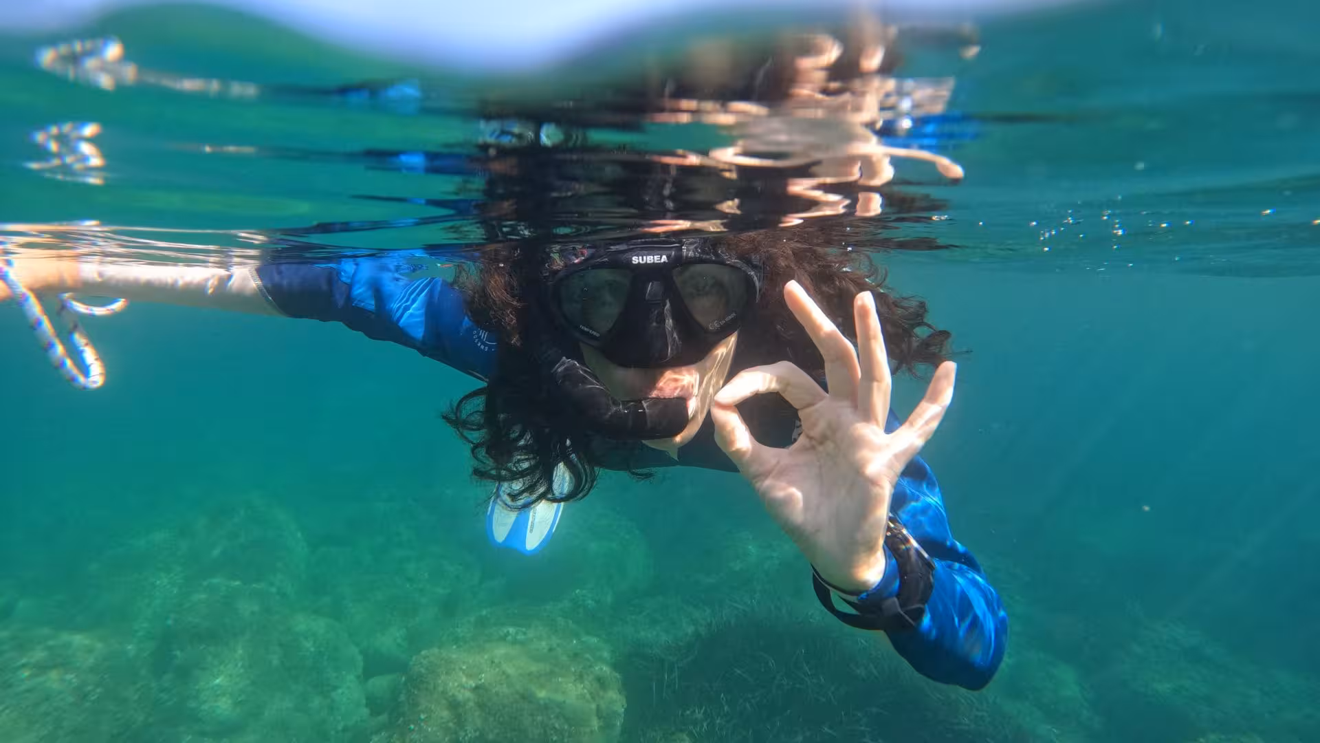 Snorkeler in Cala Gonone gives an OK sign, enjoying the clear waters and marine beauty of the Orosei Gulf.
