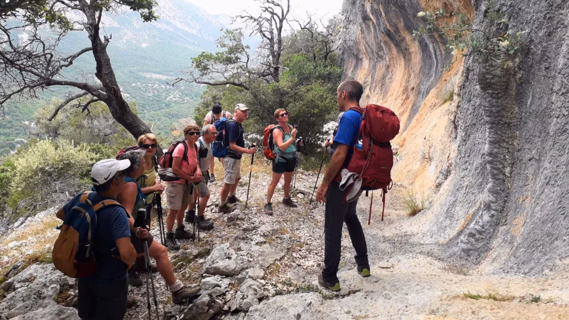 Group of hikers with guide on rocky trail in Cala Gonone, enjoying panoramic views on the trek to Tiscali.