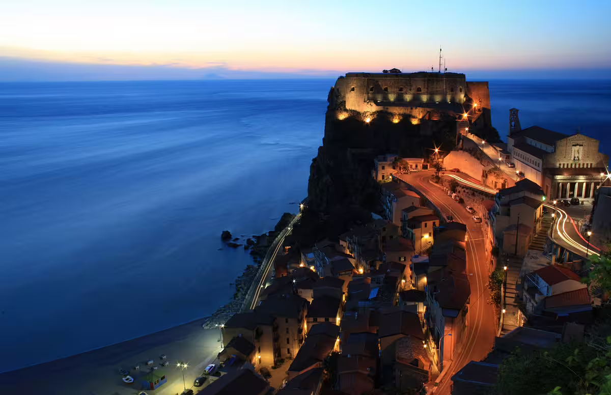 Sunset view of Scilla’s illuminated castle and coastline on Calabria self drive tour along the Tyrrhenian Sea