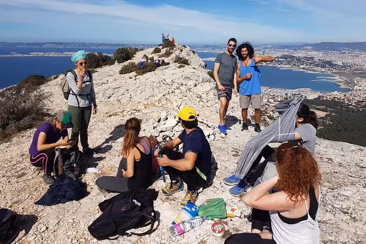 Group resting on a Calanques ridge with Marseille sea views, picnic break on the best Calanques 3-day hike