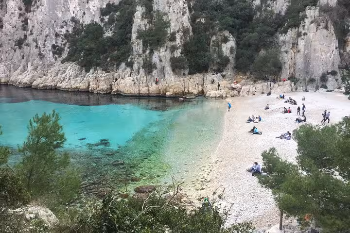 Pebble beach and clear lagoon beneath limestone cliffs in Calanques National Park, a highlight of a 3-day trip