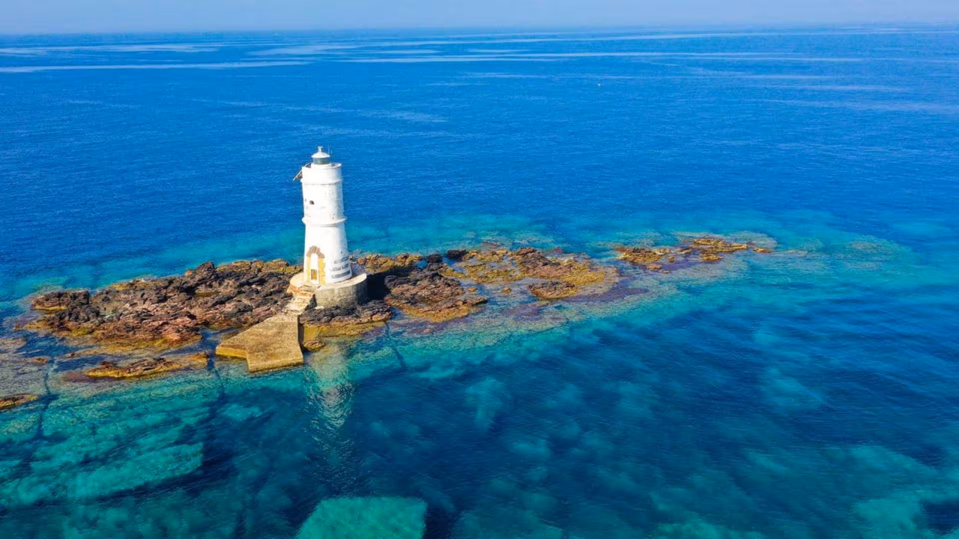 Discover the picturesque lighthouse of Calasetta surrounded by clear turquoise waters, ideal for scooter tours.
