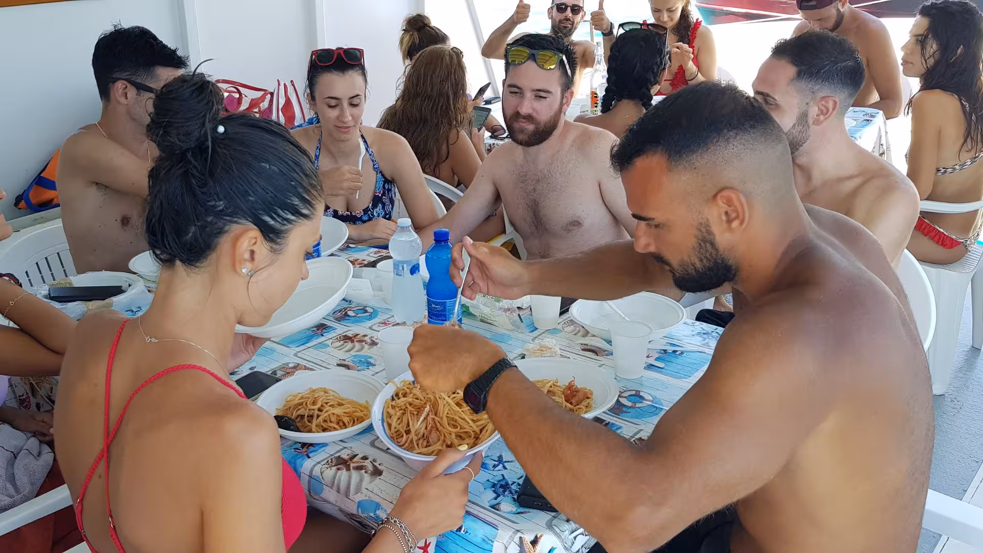 Tourists enjoying a pasta meal onboard during the San Pietro Island fishing boat tour from Calasetta.