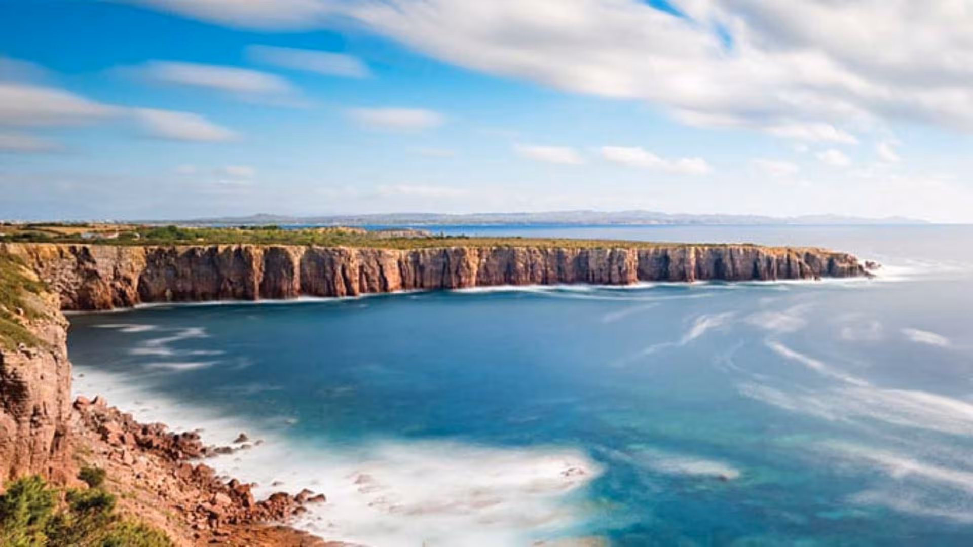 Explore stunning coastal cliffs in Calasetta on a scooter, offering breathtaking ocean views and adventure.