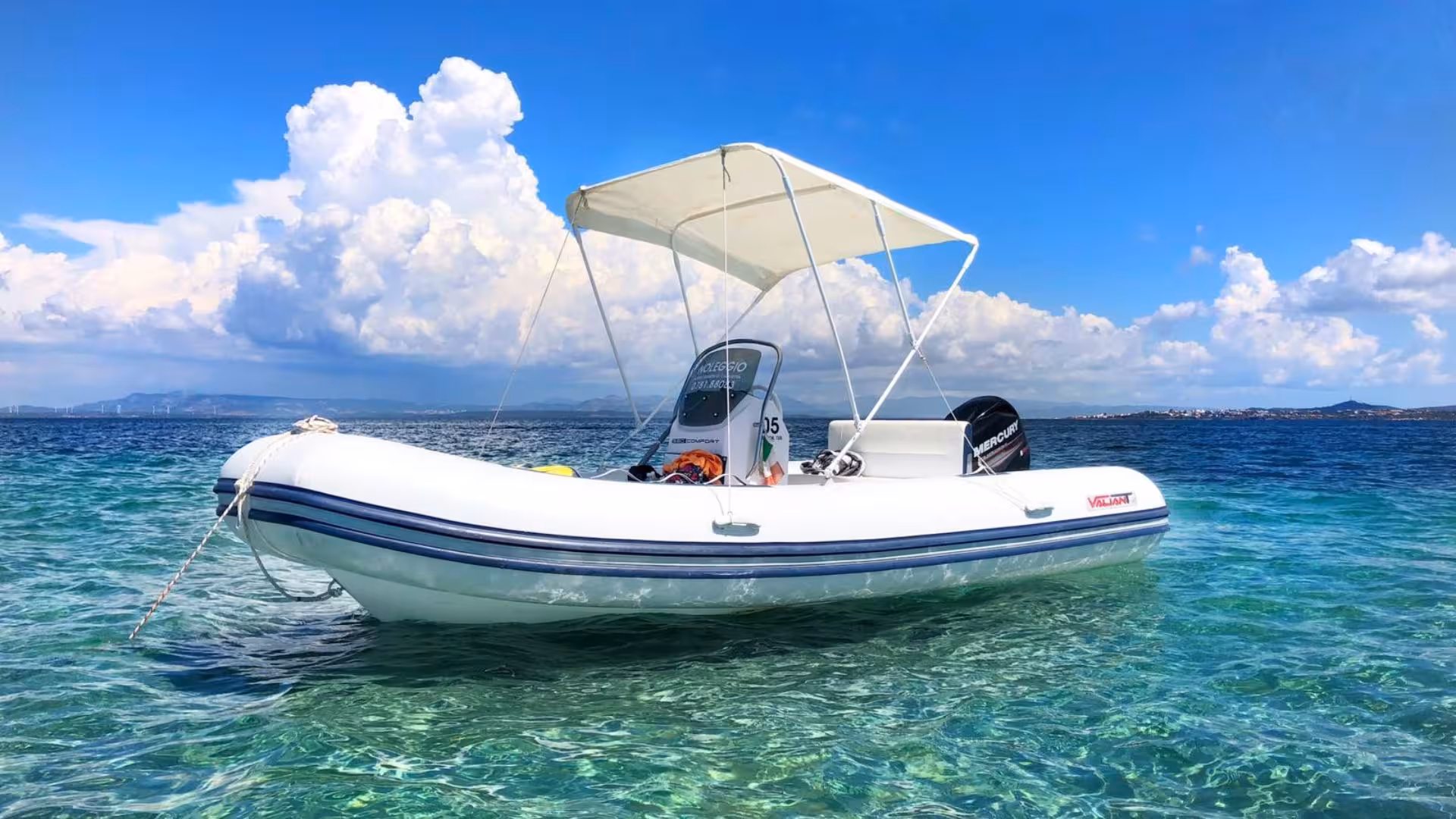 White RIB boat anchored in the clear turquoise waters of Calasetta under a bright blue sky, ideal for hire.