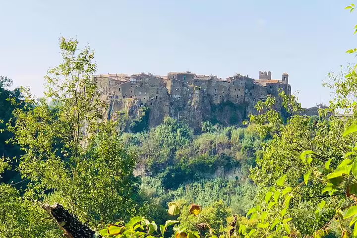 Panoramic view of Calcata’s ancient stone houses and castle rising above green valley woods on a Rome VIP private guided excursion