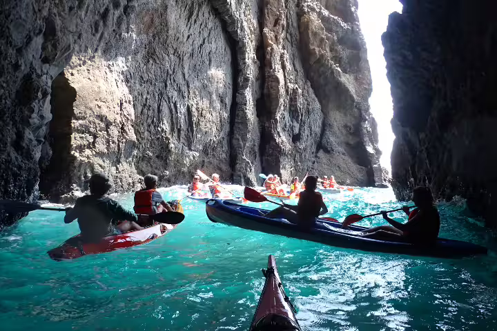 Kayakers exploring stunning sea caves and clear turquoise waters during a Calheta Kayak Tour adventure in Madeira.