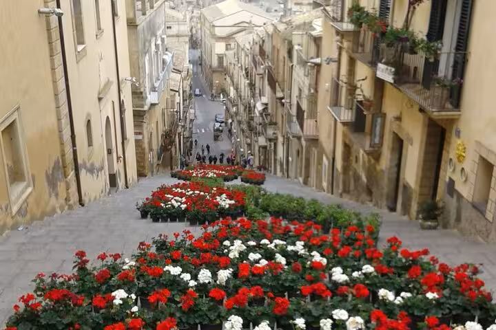 Vibrant floral staircase in Caltagirone, showcasing colorful blooms amidst historic architecture on a sunny day.