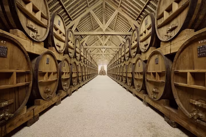 Large oak calvados aging barrels lining a long wooden warehouse cellar in Normandy