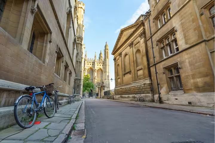 Narrow Cambridge street with bicycles leaning against historic stone university buildings and Gothic chapel in background