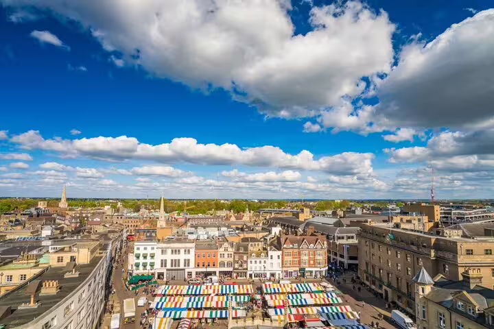 Aerial view of Cambridge city centre market square with colourful striped stalls and historic buildings