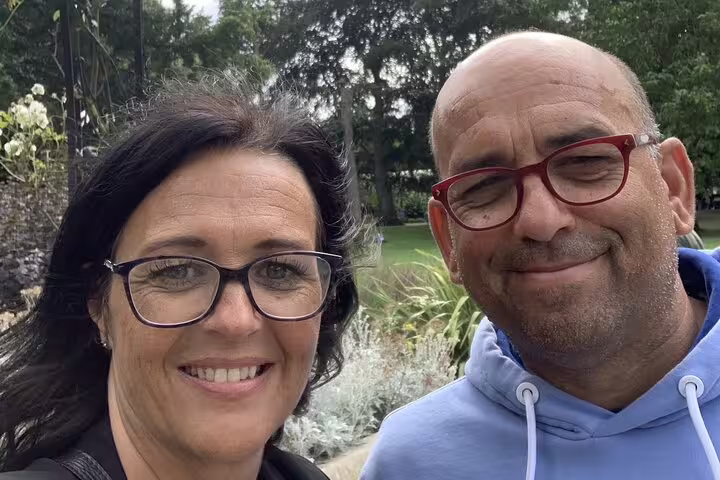 Smiling couple taking a selfie outdoors in a Cambridge park during a self-guided mystery tour