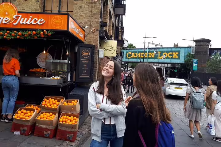 Visitors enjoy a vibrant day at Camden Lock with fresh orange juice stands, capturing the essence of London's lively markets.