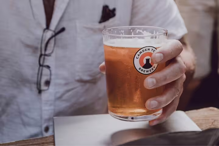A person holds a pint of beer from Camden Town Brewery, capturing the vibrant local scene on a London private tour.