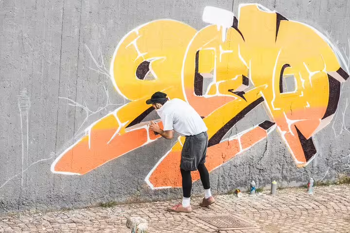 Street artist creating vibrant graffiti on a wall in Camden Town, capturing the essence of London's unique art scene and cultural tours.