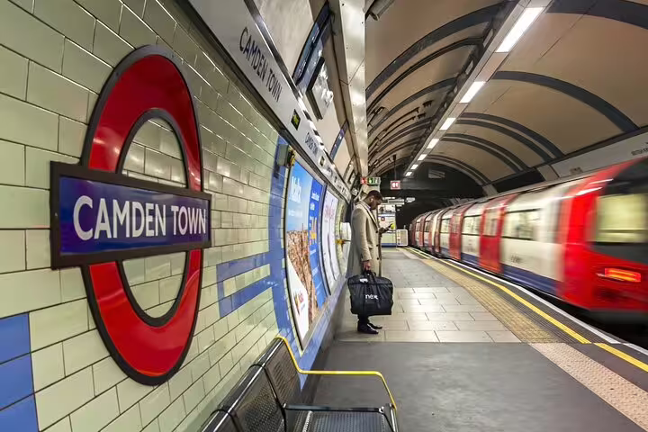 Camden Town Underground Station platform with a passing train, capturing the essence of London’s vibrant markets and street art scene.