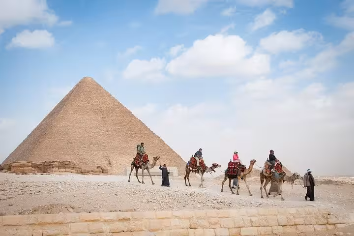 Camel caravan passing the Great Pyramid of Giza, iconic Egypt day tour from Cairo with desert views