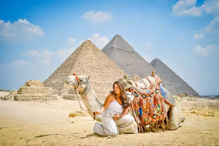 Traveler with decorated camel in front of the Giza pyramids on a full-day Cairo day trip from Sharm El Sheikh by bus
