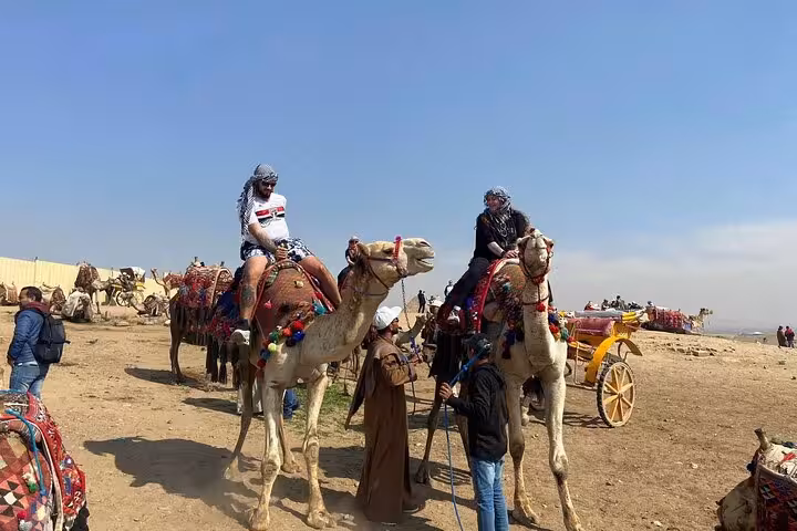 Visitors riding decorated camels near Cairo desert camp, classic camel ride experience on Cairo tour