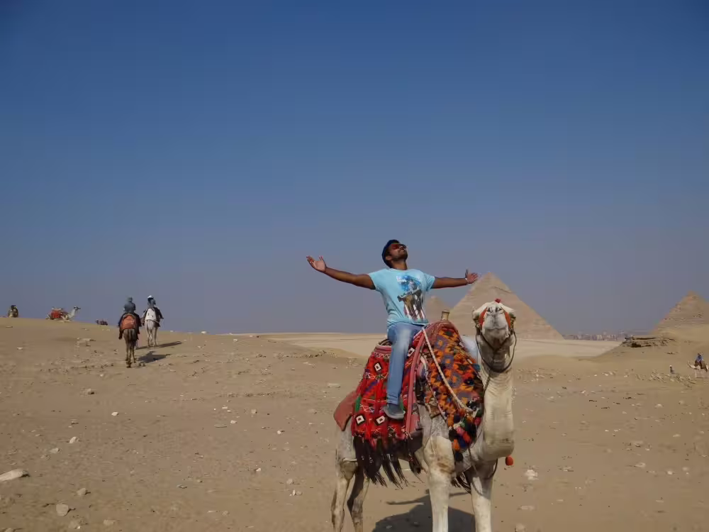 Camel ride at Giza Pyramids during Cairo day trip with flights from Sharm El Sheikh, desert panorama