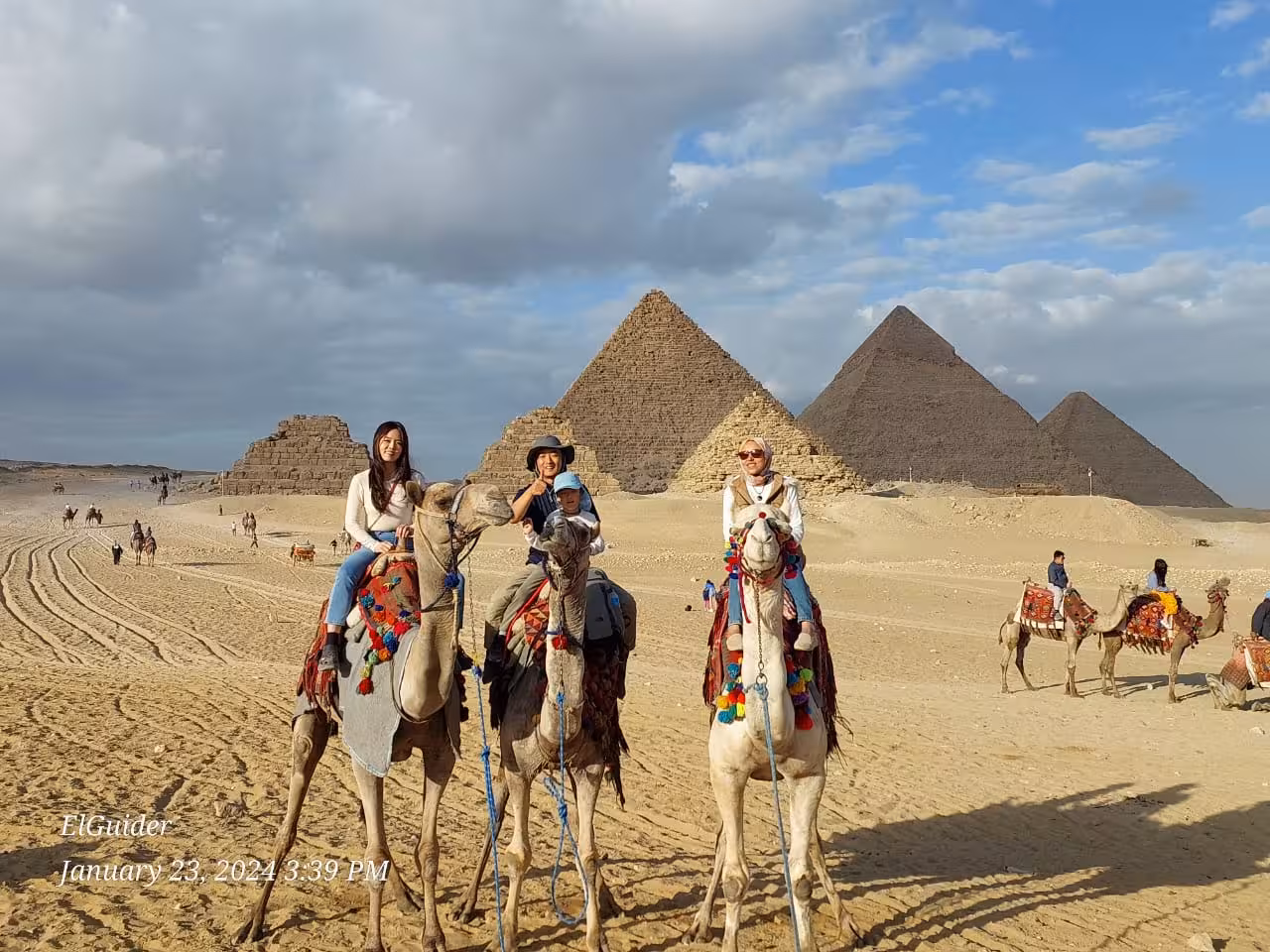Camel ride at Giza Pyramids with travelers on private Cairo tour, iconic desert views near the pyramids