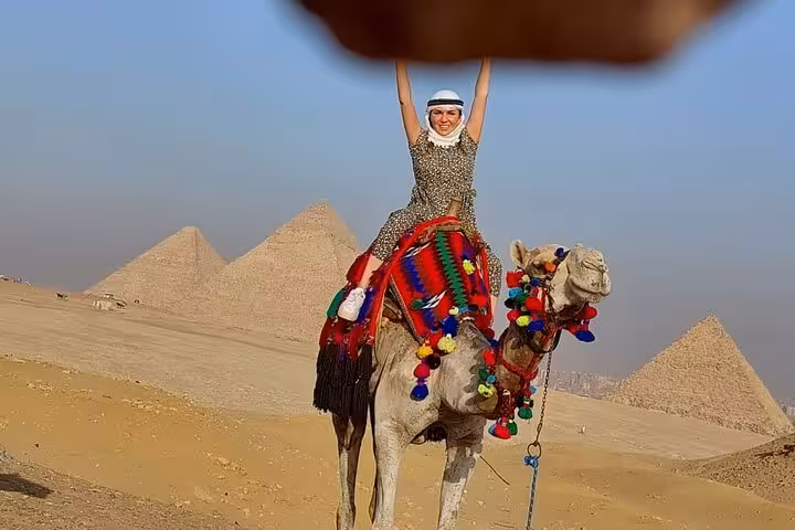 Camel ride photo at Giza Pyramids during Hurghada to Cairo tour, desert view with pyramids behind