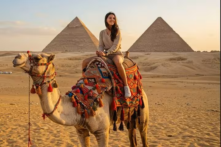 Traveler riding camel at Giza Pyramids at sunset, part of Grand Egyptian Museum, Sphinx and lunch tour