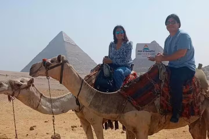 Tourists on camel ride at Giza Pyramids, Egypt, with transfers for sunrise or sunset desert tour