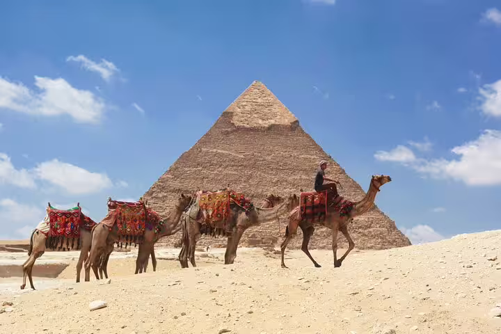 Camel ride at the Great Pyramid of Giza under blue skies, classic Cairo day tour photo stop