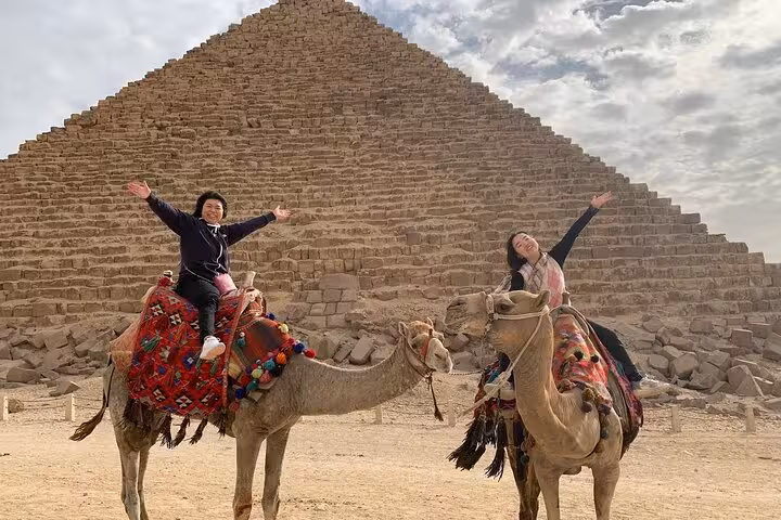Travelers on a camel ride in front of the Great Pyramid of Giza on a private Pyramids & Sphinx tour, Cairo