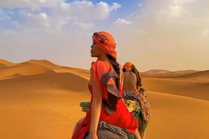 Camel ride across golden Sahara dunes in Morocco on the 3 days desert tour from Fes to Marrakech at sunset
