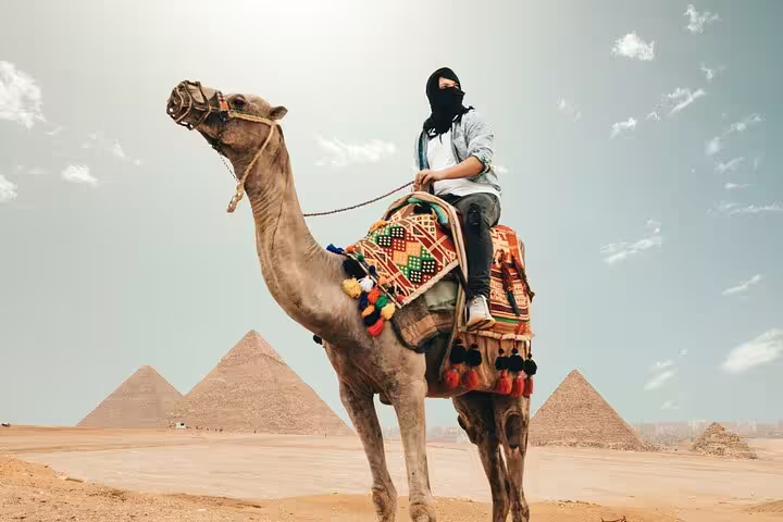 Camel rider with the Giza Pyramids in Cairo, Egypt, on a day trip tour to Giza, Citadel and Old Cairo