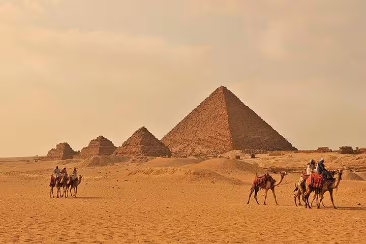 Camel riders crossing the Giza plateau at sunset, ideal Cairo photo session add-on tour shots