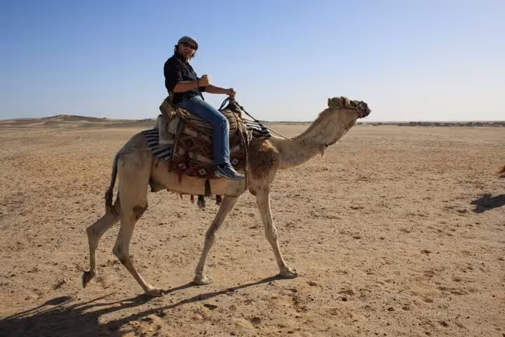 Traveler riding a camel in the Hurghada desert on a one-hour camel safari with hotel transfer included
