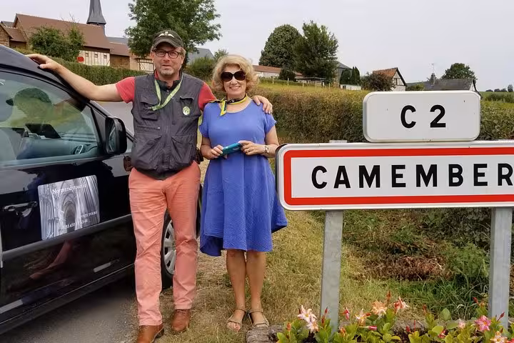 Guide and guest by Camembert village sign in Normandy, private Bayeux specialties food tour tasting route