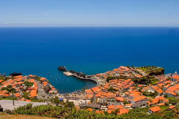 Aerial view of Câmara de Lobos, Madeira, showcasing vibrant terracotta rooftops and the deep blue Atlantic Ocean.