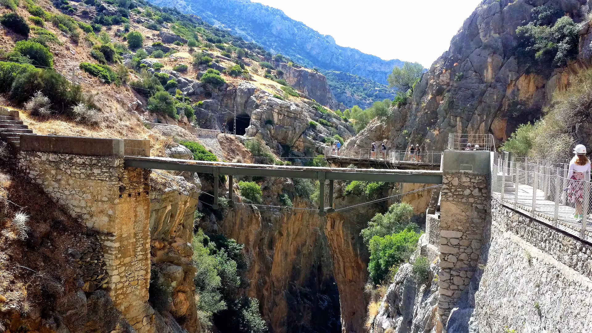 Caminito del Rey group walking tour crossing the cliffside bridge in El Chorro gorge, Malaga, Spain