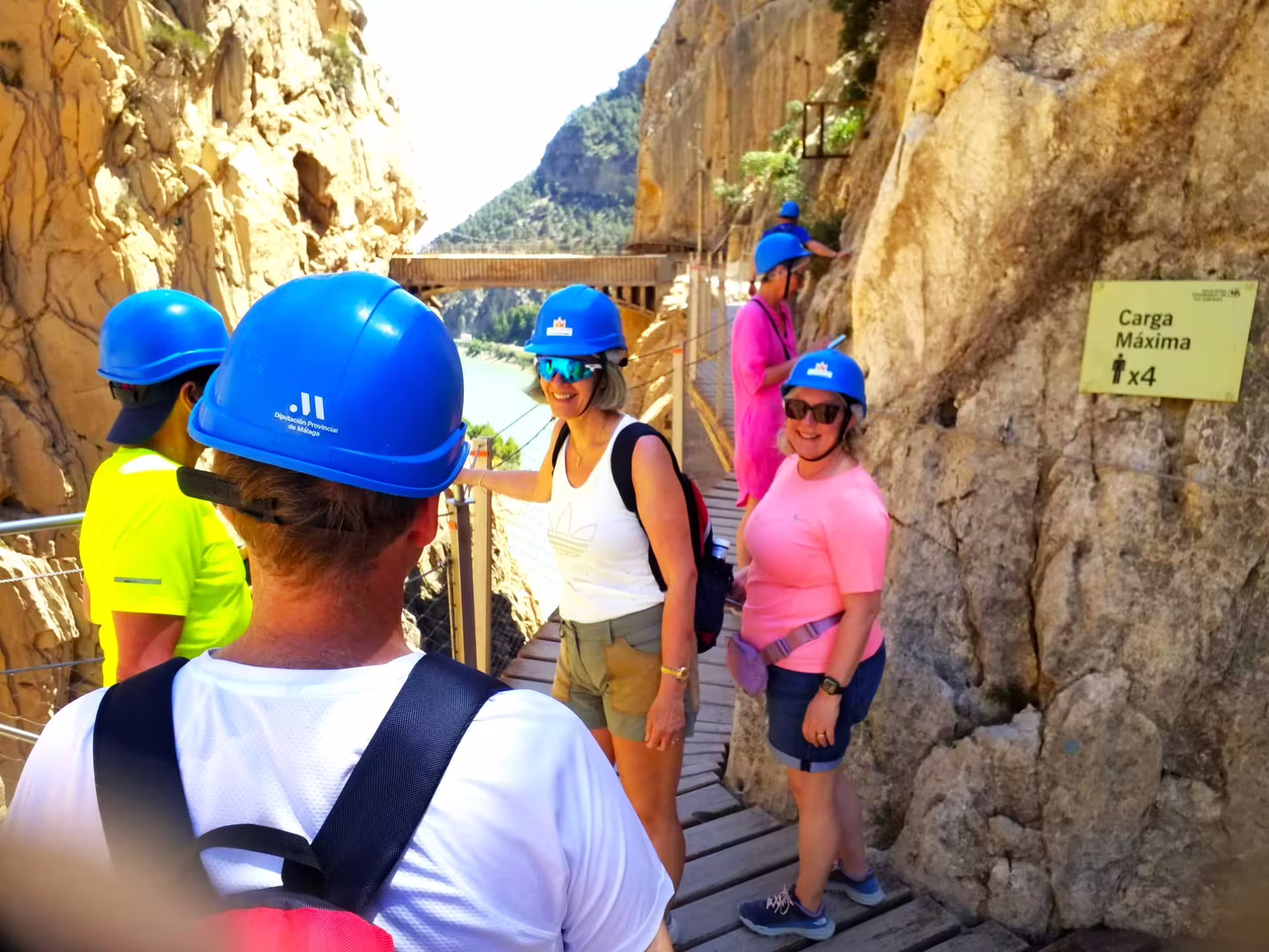 Group in helmets on Caminito del Rey cliff walkway with reservoir views, private guided hike in Malaga
