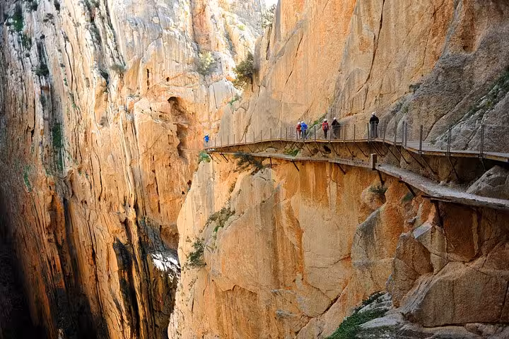 Adventurers on the narrow Caminito del Rey path along steep cliffs, featured in a small group tour from Malaga.
