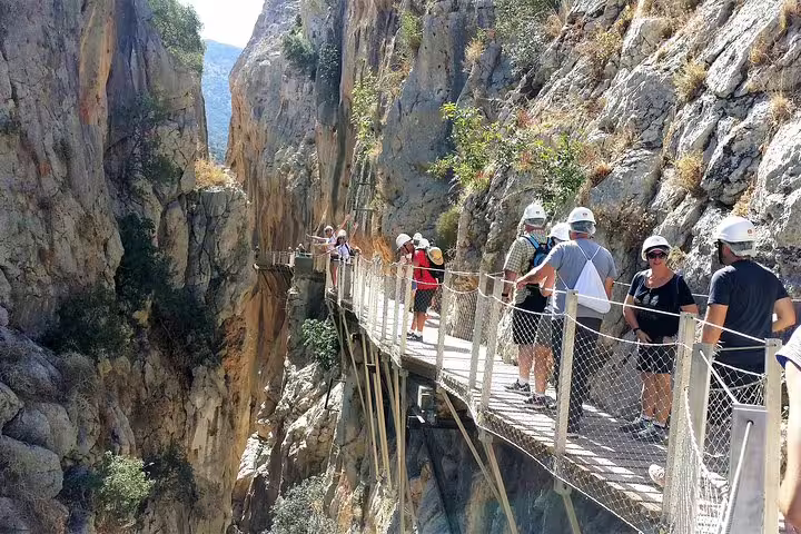 Hikers with safety helmets on Caminito del Rey cliff path, private tour with pickup from Marbella or Malaga