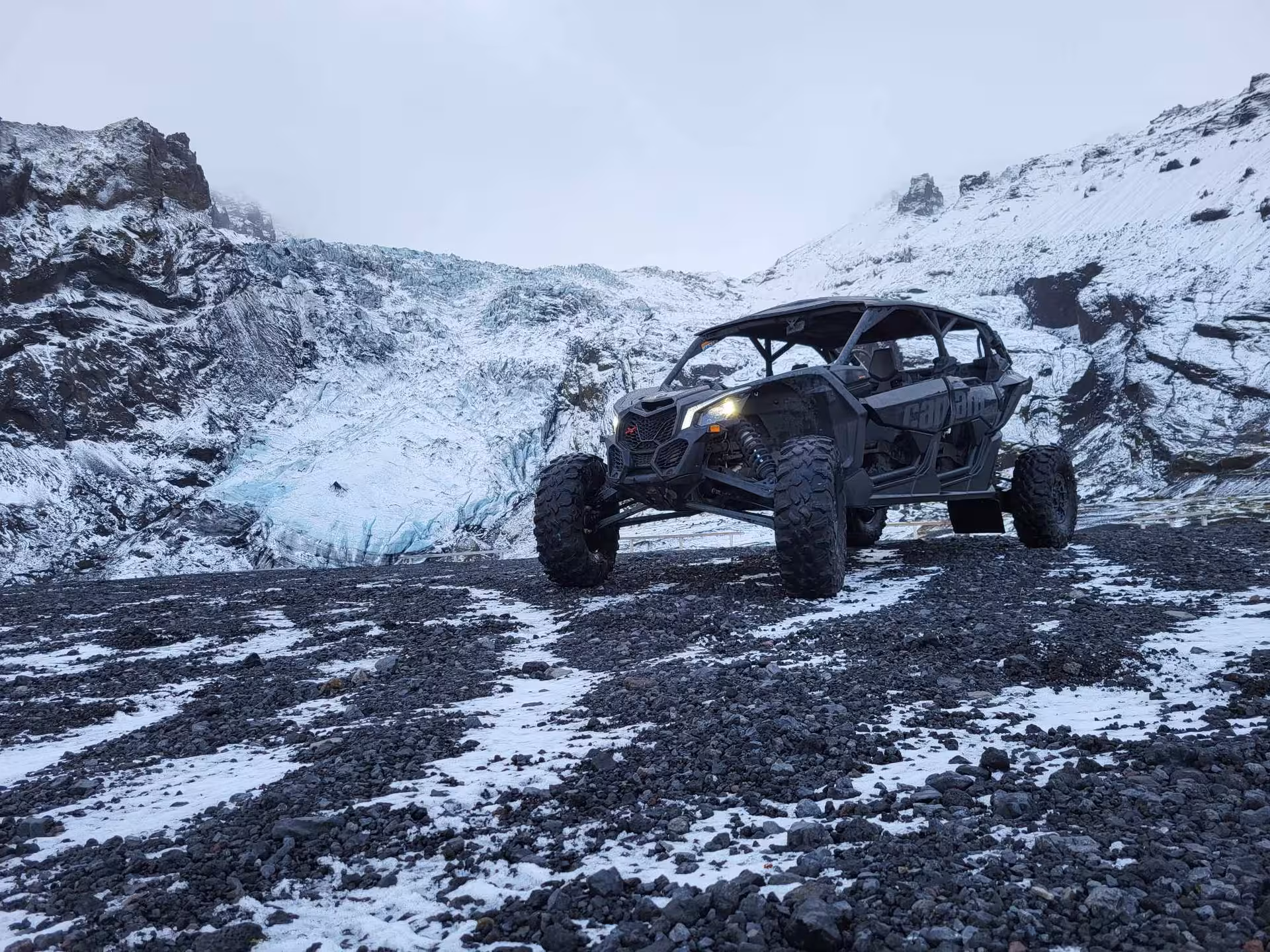 Can-Am buggy ATV on rocky volcanic terrain with glacier and snowy mountains in Iceland
