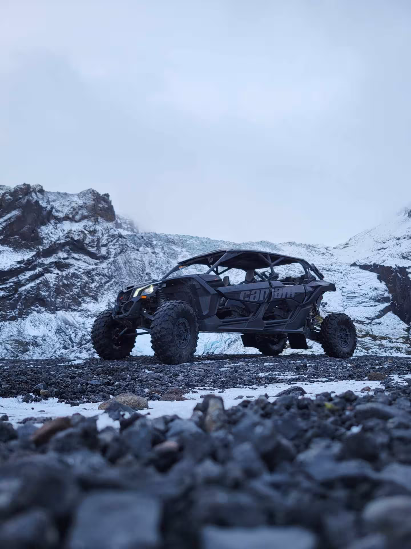Can-Am buggy UTV parked on rocky terrain with snow-covered mountains in Iceland