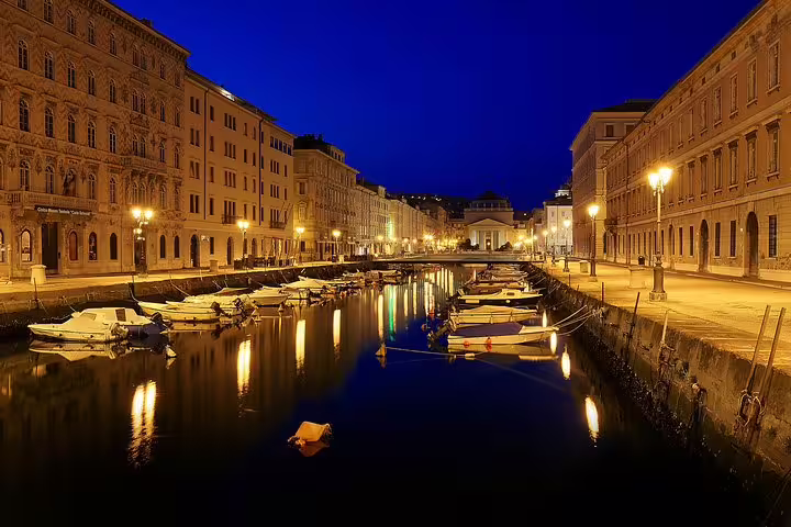 Canal Grande at night in Trieste with Habsburg-era palaces and moored boats on a private guided walking tour route