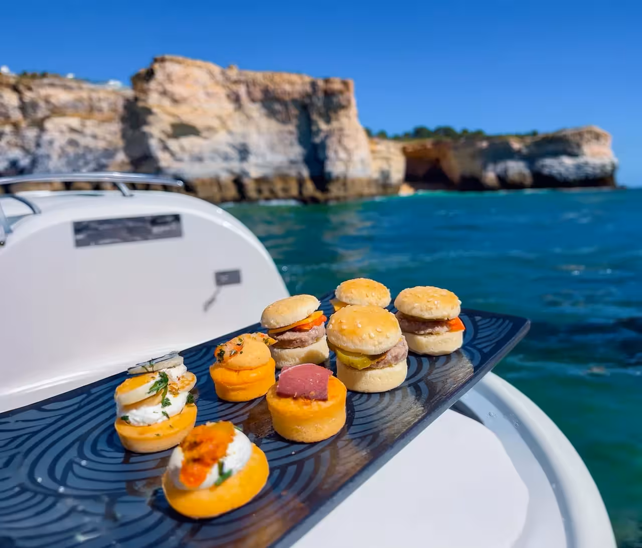 Fresh Portuguese food tasting platter served on a Vilamoura boat tour with stunning Algarve sea caves backdrop