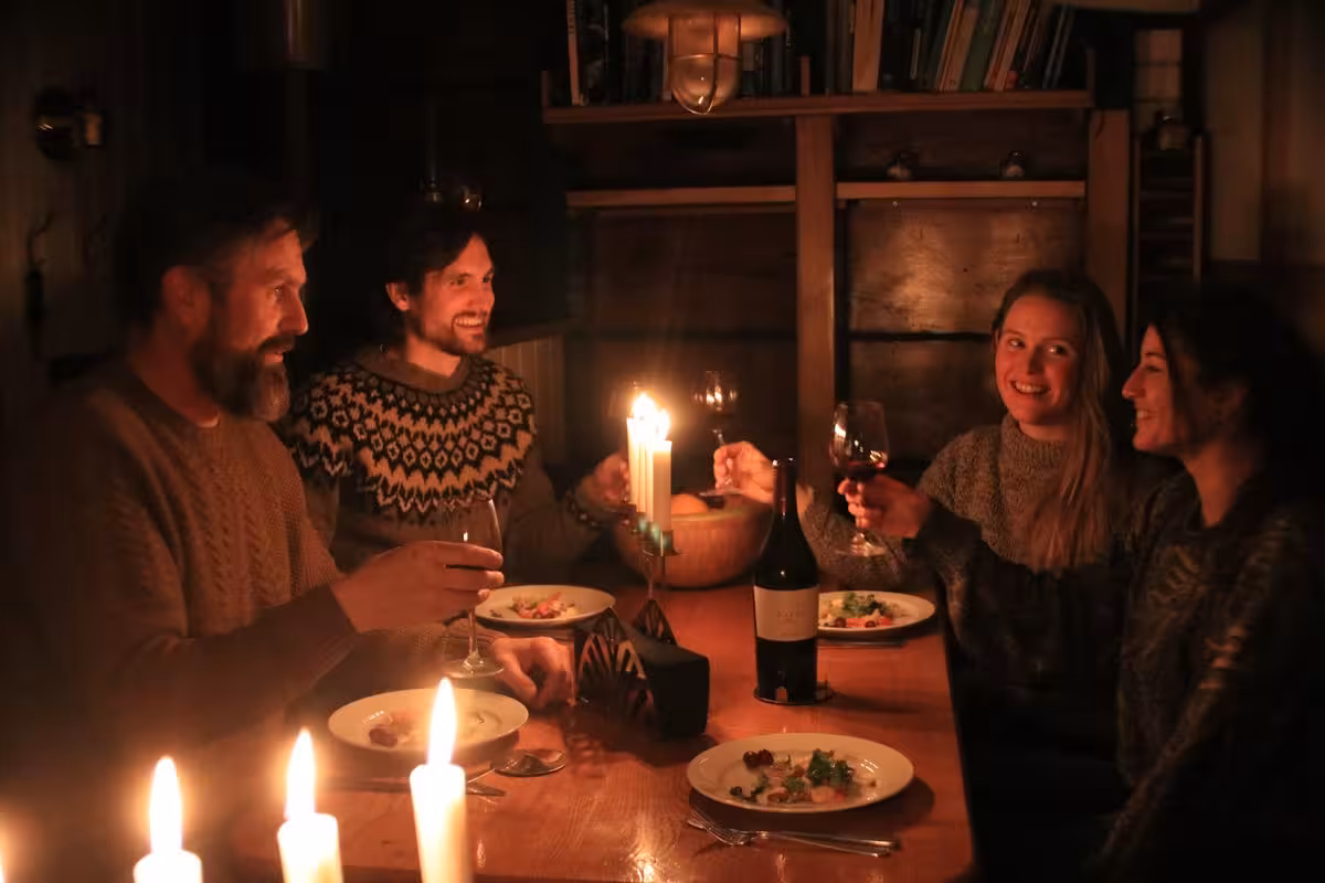 Guests enjoying elegant candlelit gourmet dinner aboard exclusive Northern Lights luxury Arctic cruise experience