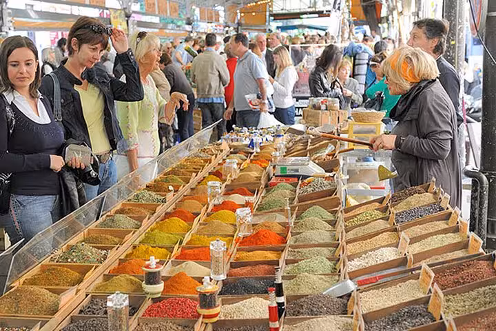 Colorful spice market stall in Cannes with shoppers browsing vibrant mounds of spices and herbs