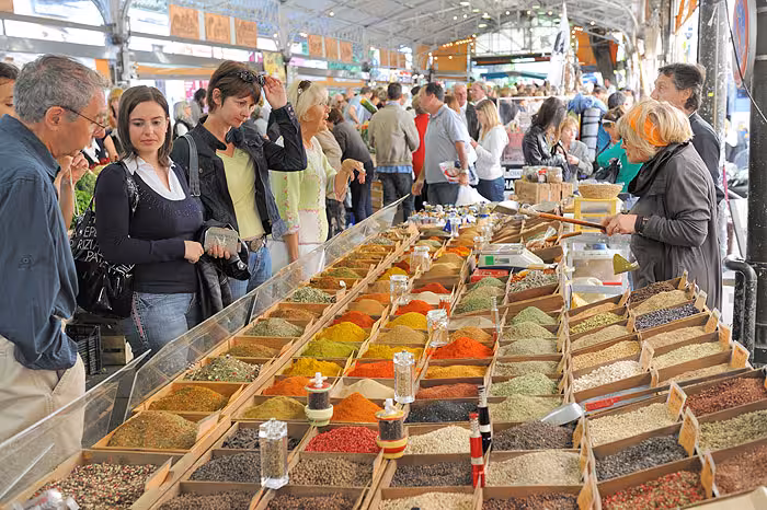 Colorful spice market stall with tourists browsing vibrant mounds of spices in Cannes French Riviera