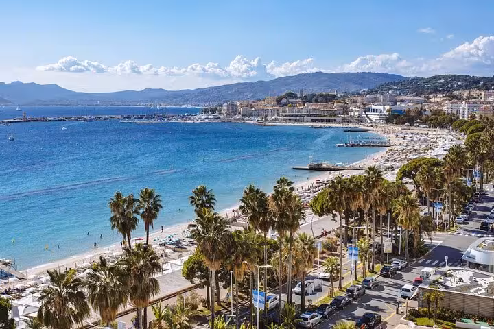 Aerial view of Cannes beach and turquoise Mediterranean Sea along the French Riviera coastline with palm trees