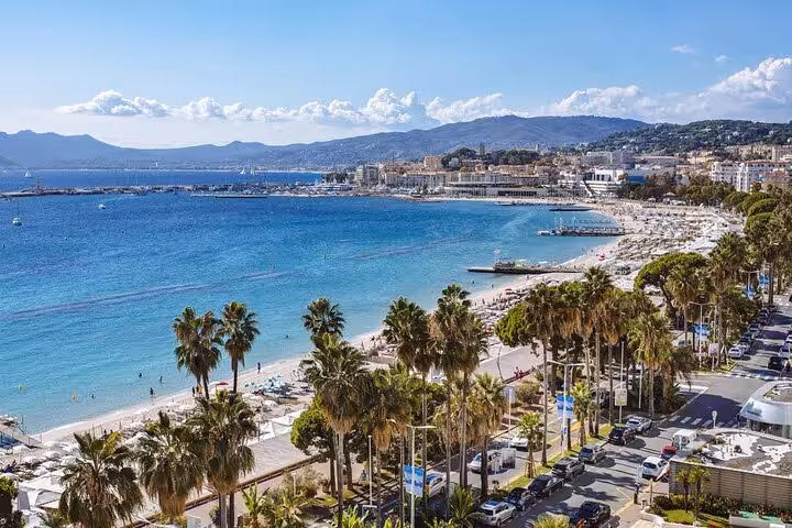 Panoramic view of Cannes beach on the French Riviera with turquoise water, palm trees, and marina
